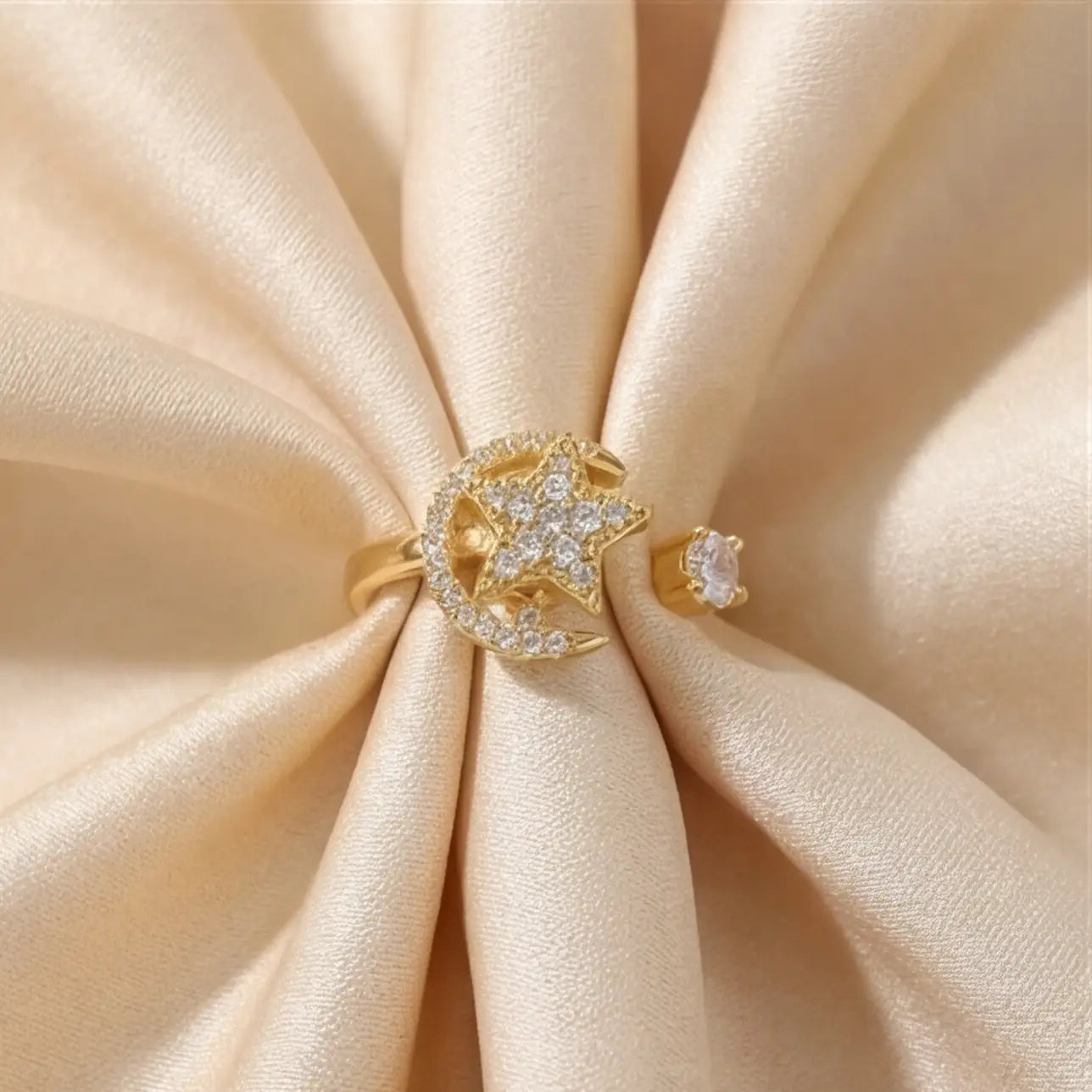 Centered top-down view of the gold Pausa spinning sun star fidget calm ring nestled in soft silk material.
