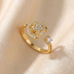 A diagonal perspective of a gold Calm spinning sun and star ring resting on textured satin.