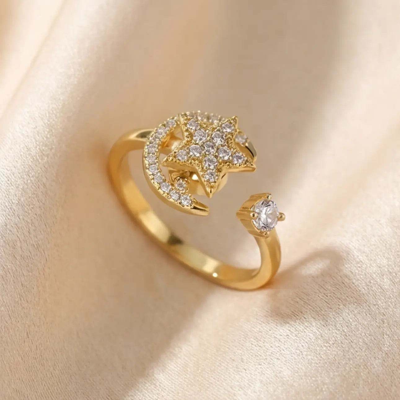 A diagonal perspective of a gold Calm spinning sun and star ring resting on textured satin.