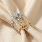 A pair of gold and silver Pausa spinning sun star fidget calm rings resting on champagne silk folds.