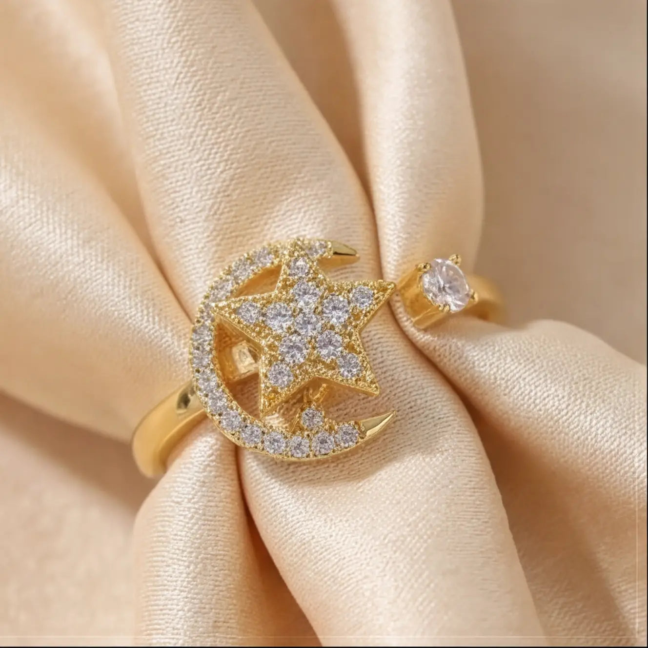 An upright gold Calm spinning sun ring showcasing a pavé star center against draped silk.
