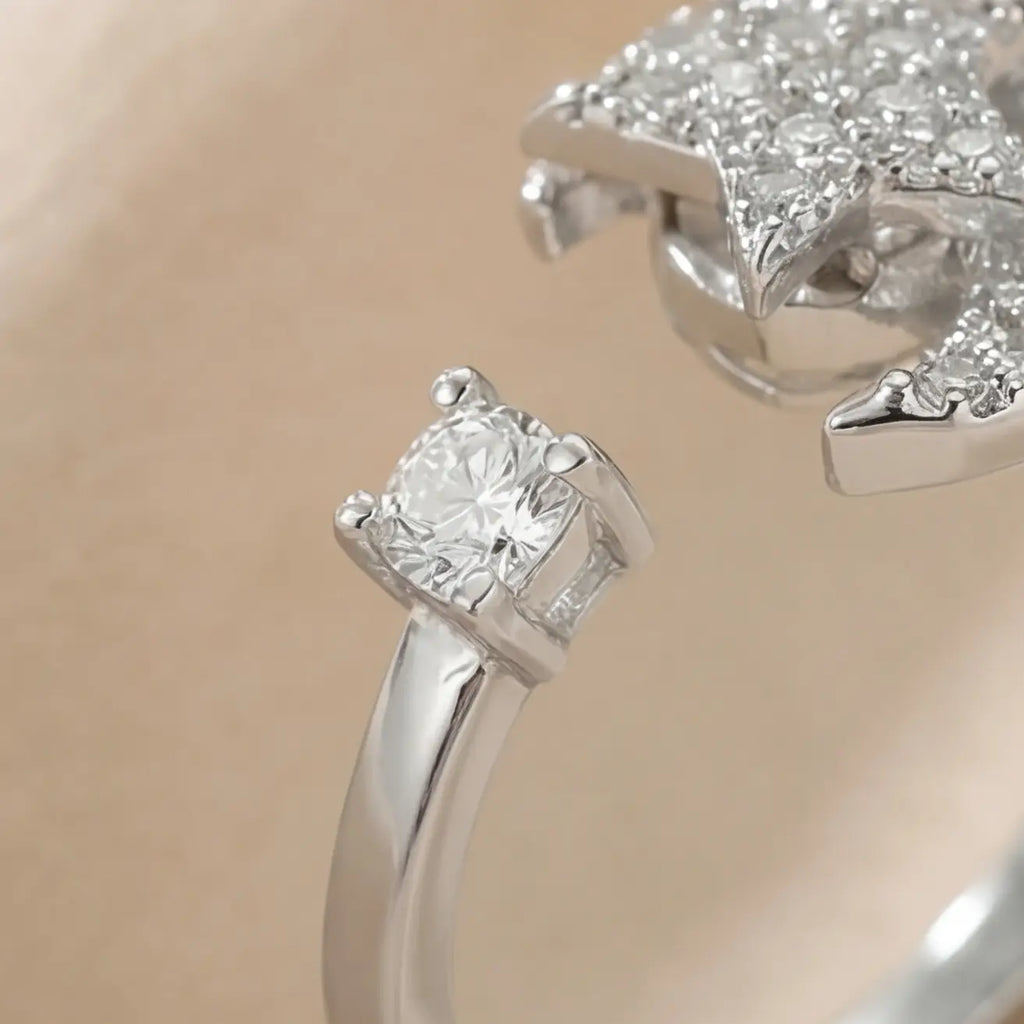 Detailed macro shot of the silver Pausa spinning sun star fidget calm ring focusing on the prong-set solitaire crystal.