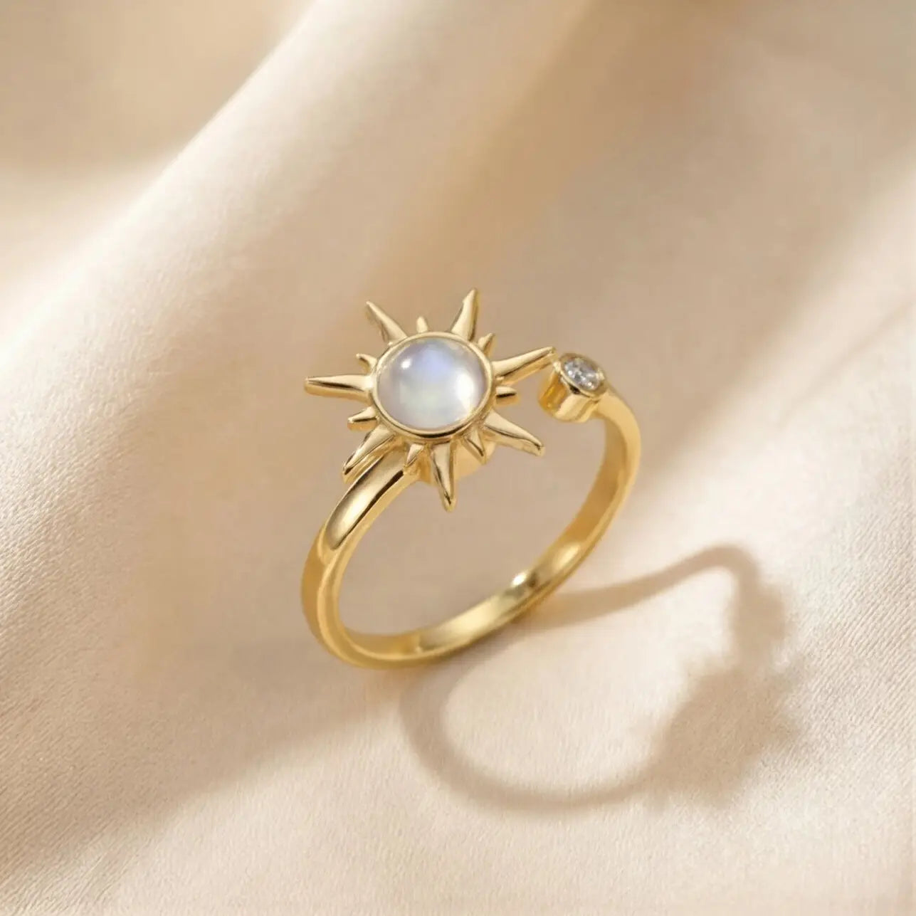 Gold sunburst moonstone calm ring on soft cream fabric background