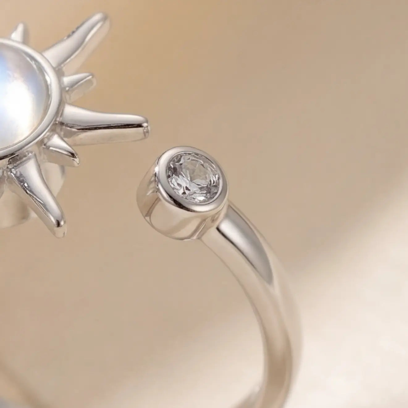 Close up of silver sunburst calm ring with bezel set clear accent stone