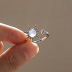 Silver sunburst moonstone calm ring held between fingers in natural light