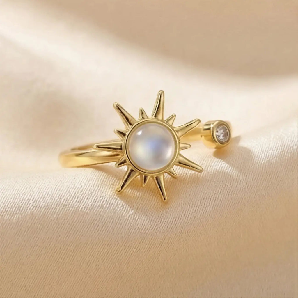 Gold sunburst calm ring with moonstone center angled on cream fabric