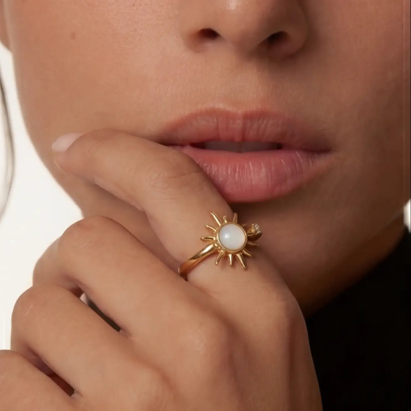 Gold sunburst moonstone calm ring worn on model hand portrait shot