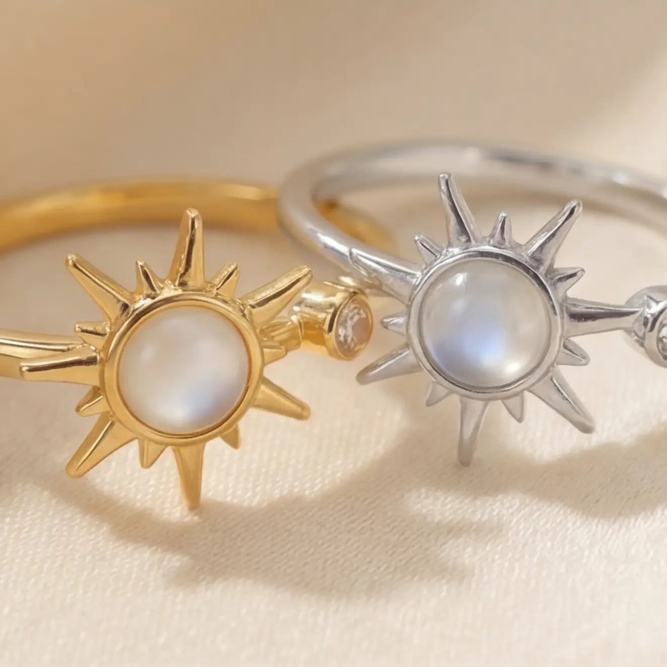 Gold and silver sunburst calm rings with moonstone center stones on cream background