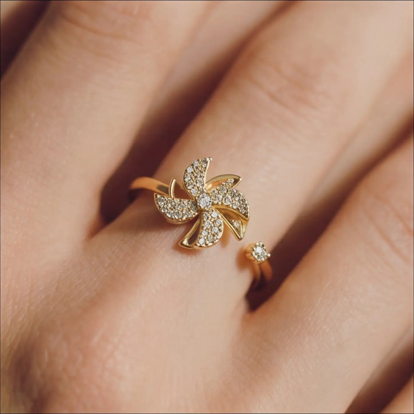 Close up of Lunela Attimo gold pavé pinwheel calm spinner ring worn on finger