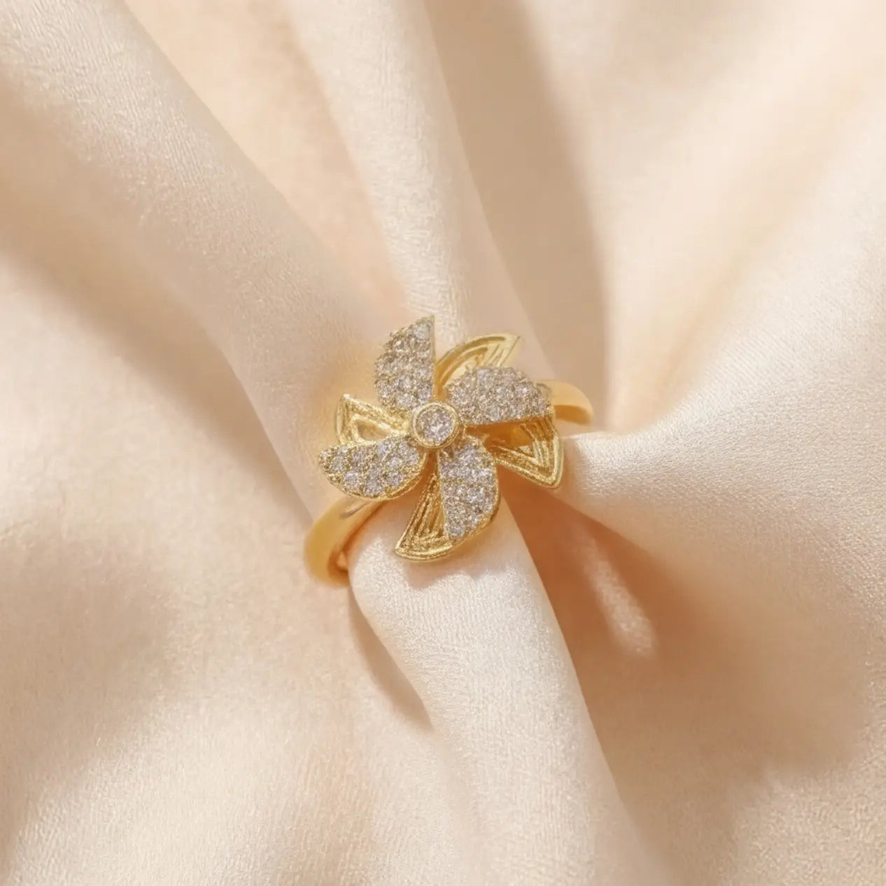 Full view of Lunela Attimo gold pavé pinwheel calm spinner ring displayed on champagne satin