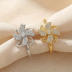 Lunela Attimo pavé pinwheel calm spinner rings in silver and gold displayed on champagne satin fabric