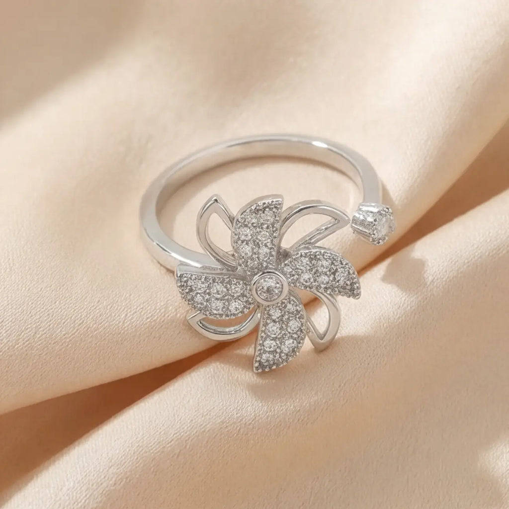 Full view of Lunela Attimo silver pavé pinwheel calm spinner ring on champagne satin fabric
