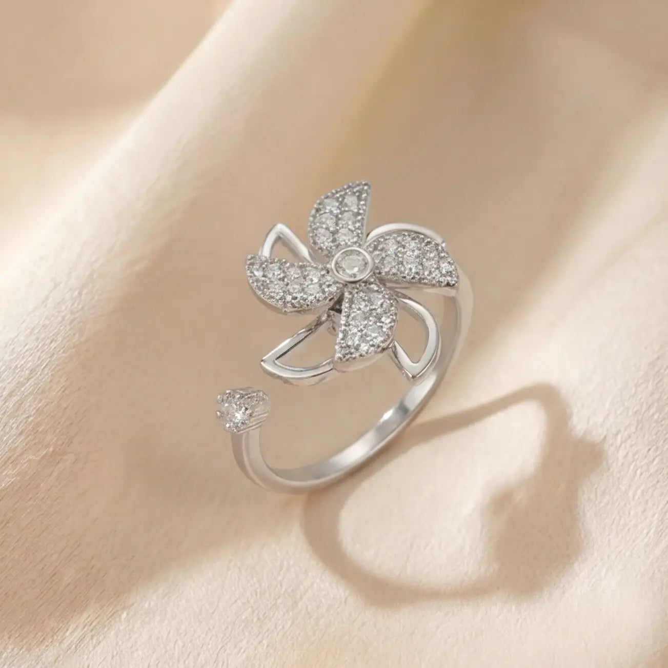 Upright product shot of Lunela Attimo silver pavé pinwheel calm spinner ring with rotating petal design