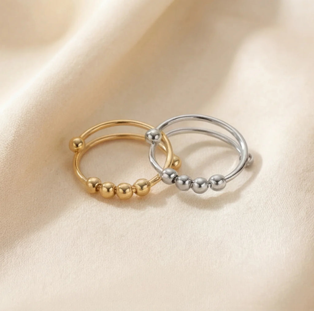 Gold and silver Centro spinner rings displayed side by side to compare finishes and color.