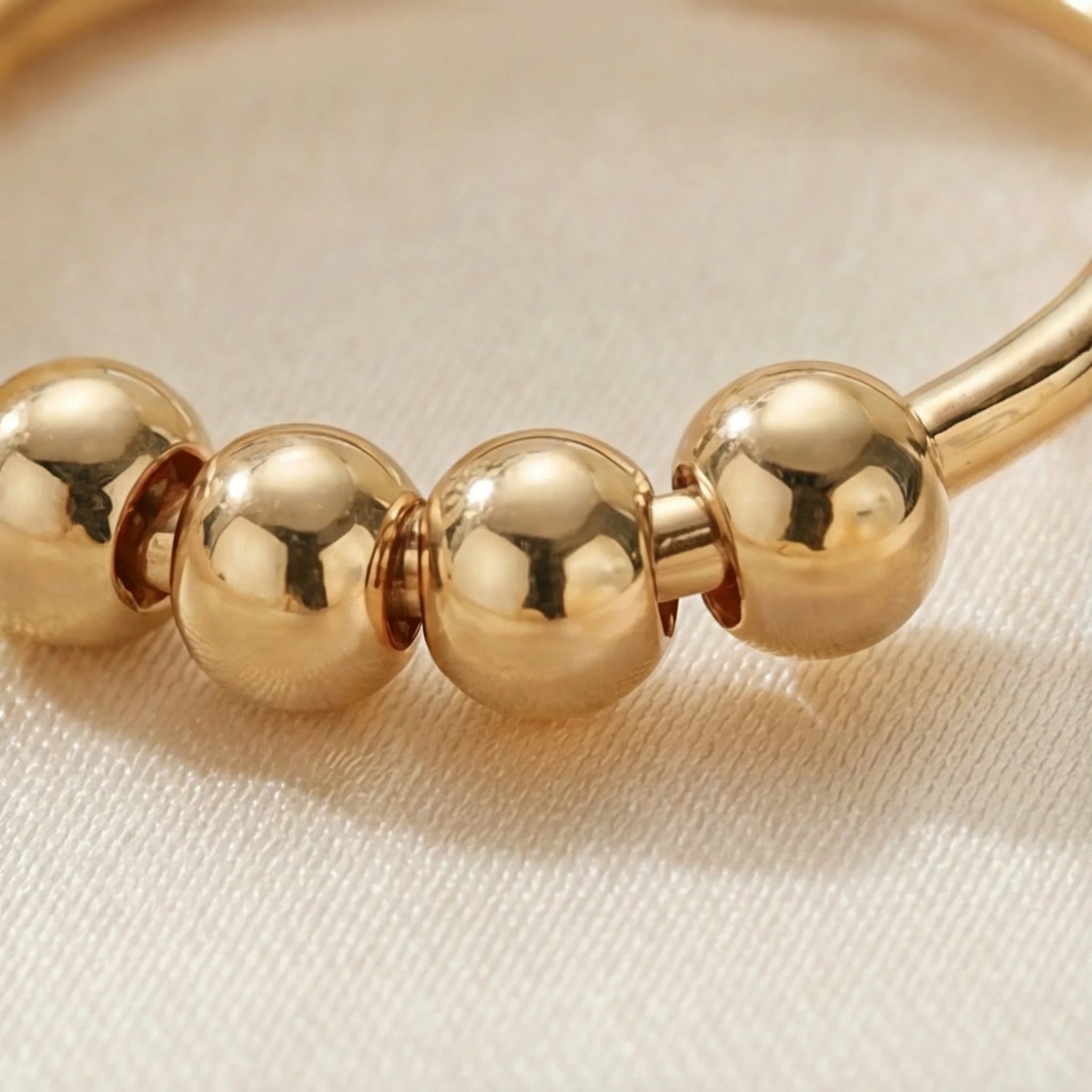 Close up of the gold LUNÉLA Centro spinner ring highlighting the polished beads designed for calm focus.