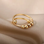 Gold LUNÉLA Centro spinner ring photographed in soft light to highlight its calming bead design.