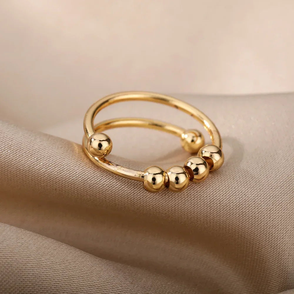 Gold LUNÉLA Centro spinner ring photographed in soft light to highlight its calming bead design.