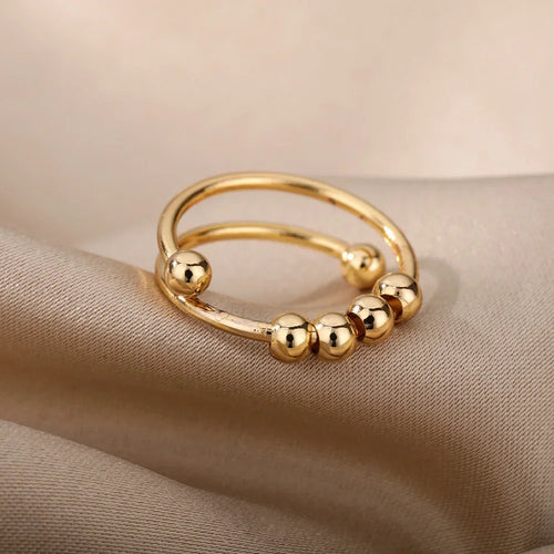 Gold LUNÉLA Centro spinner ring photographed in soft light to highlight its calming bead design.