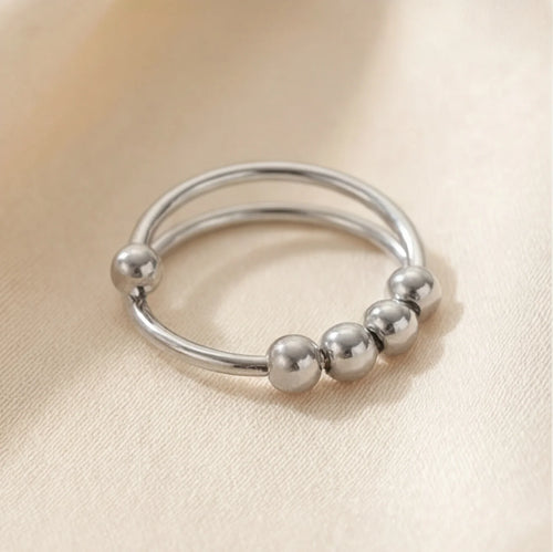 Polished silver LUNÉLA Centro spinner ring shown in a clean flat lay with smooth rotating beads.