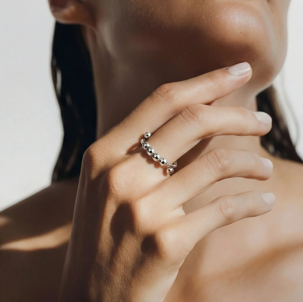 Silver LUNÉLA Centro spinner ring worn on a woman’s hand offering elegant anxiety relief.