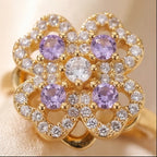 Close up of gold clover flower calm ring with purple gemstones and clear pavé stones