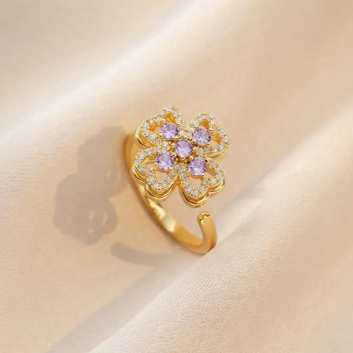 Woman wearing gold clover flower calm ring with purple gemstones