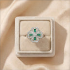 Gold clover flower calm ring with purple stones casting soft shadow on fabric