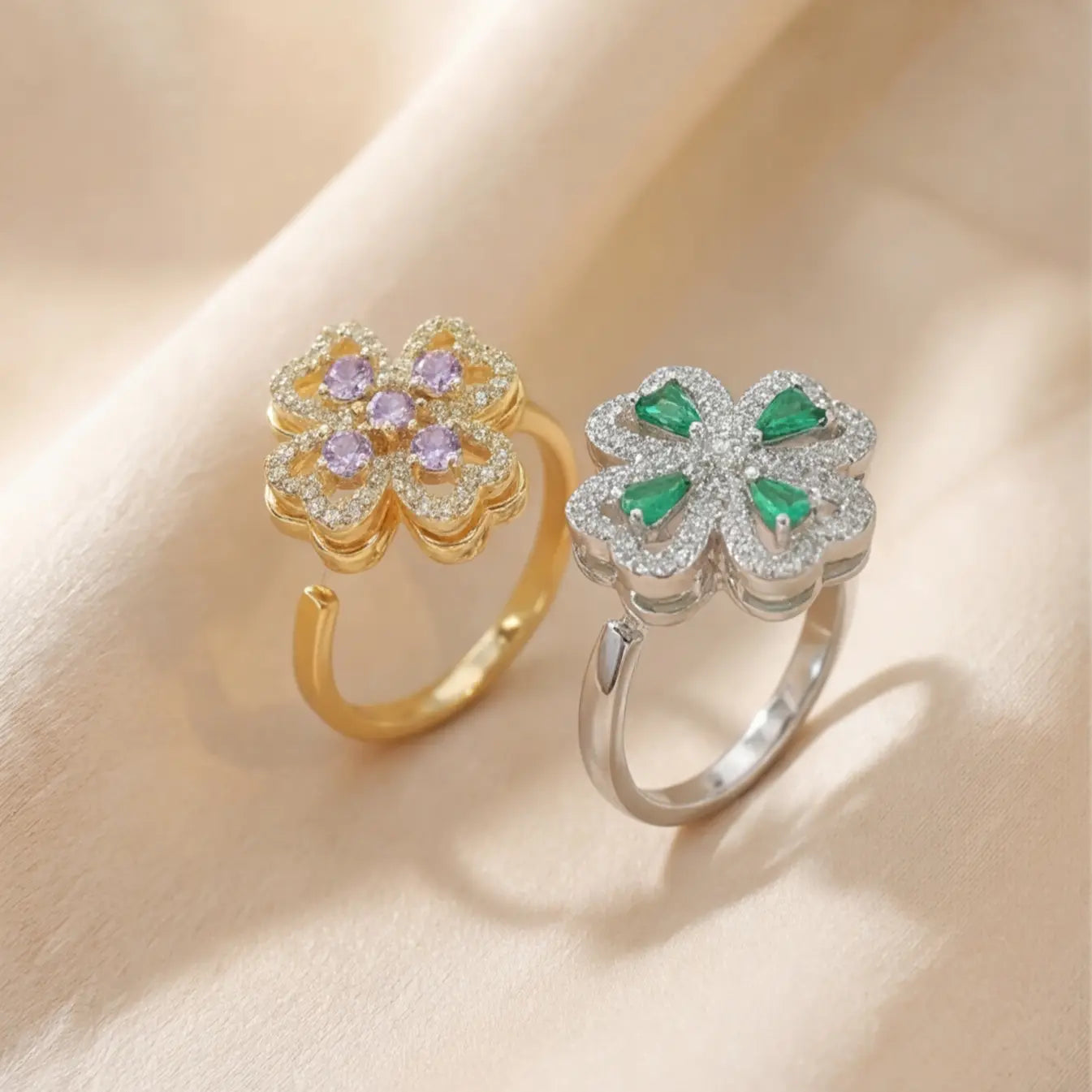 Gold purple clover calm ring and silver green clover ring side by side on silk