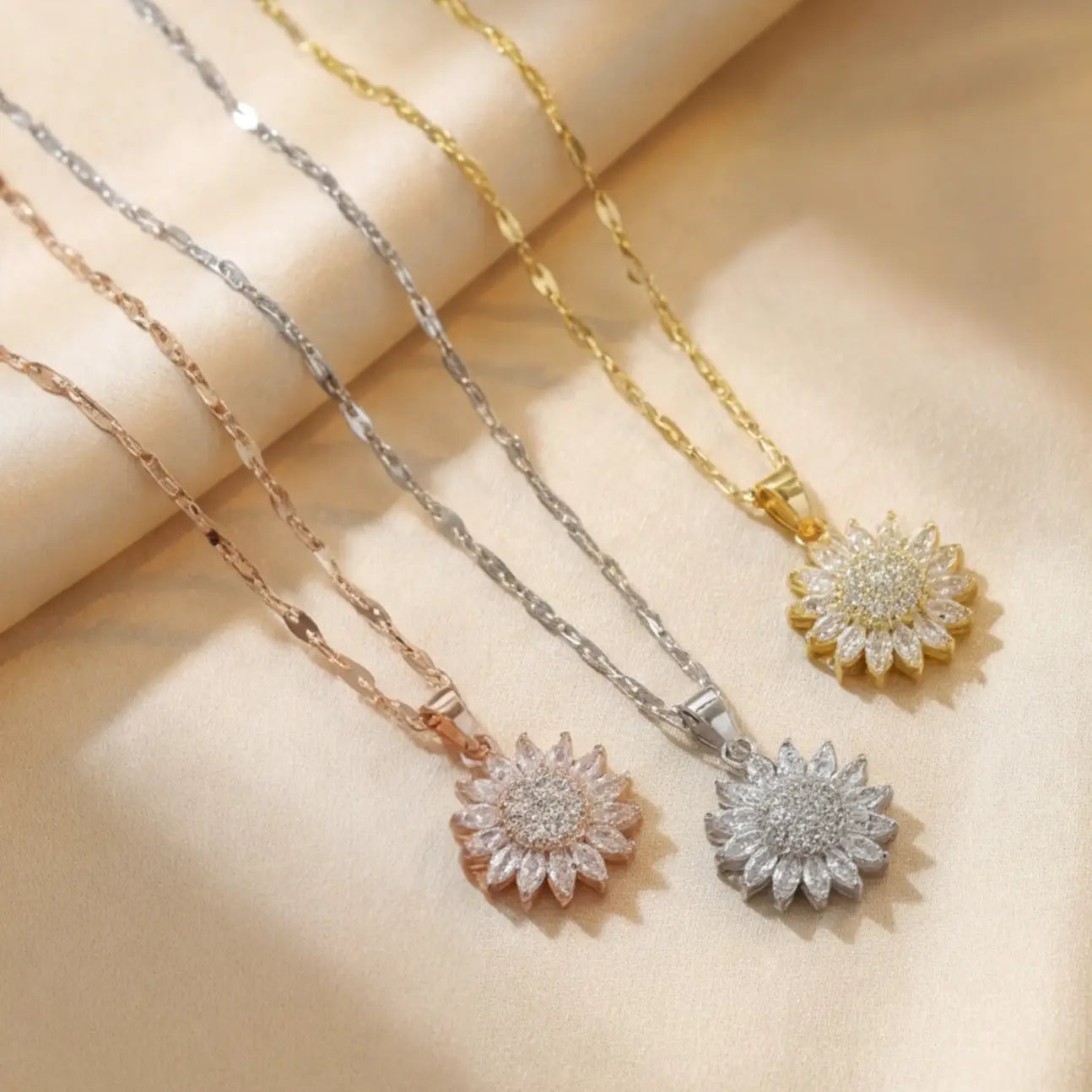 Lunela Collana crystal flower pendant necklaces displayed in three metal tones on soft champagne fabric