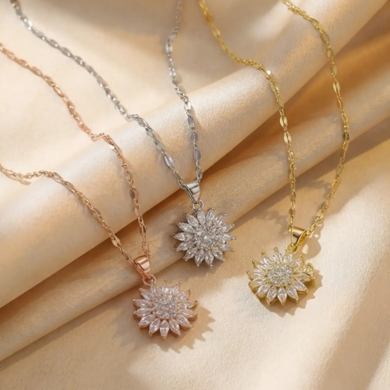 Lunela Collana flower pendant necklace shown in gold, silver and rose gold finishes on champagne satin