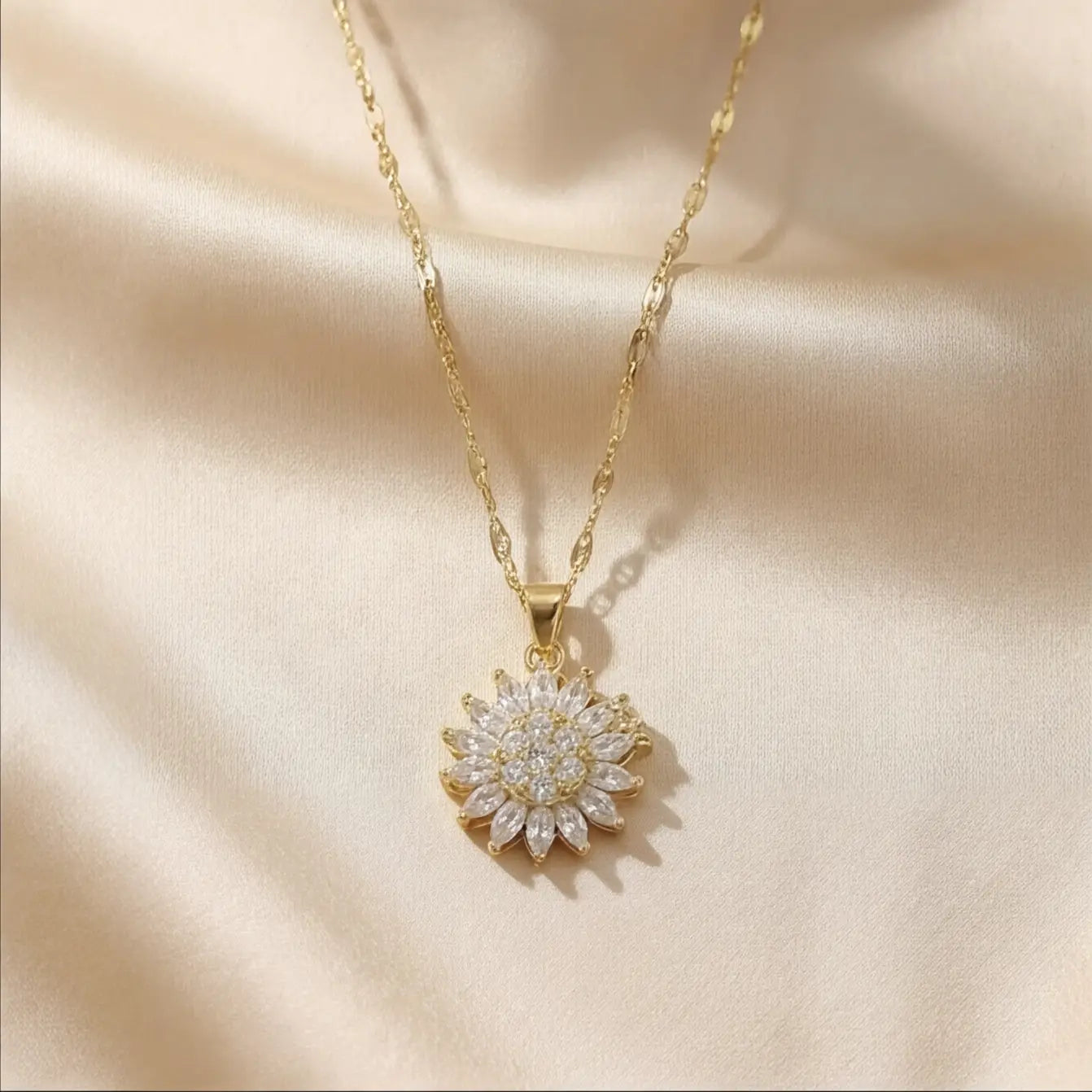 Lunela Collana gold flower pendant necklace worn on champagne satin background