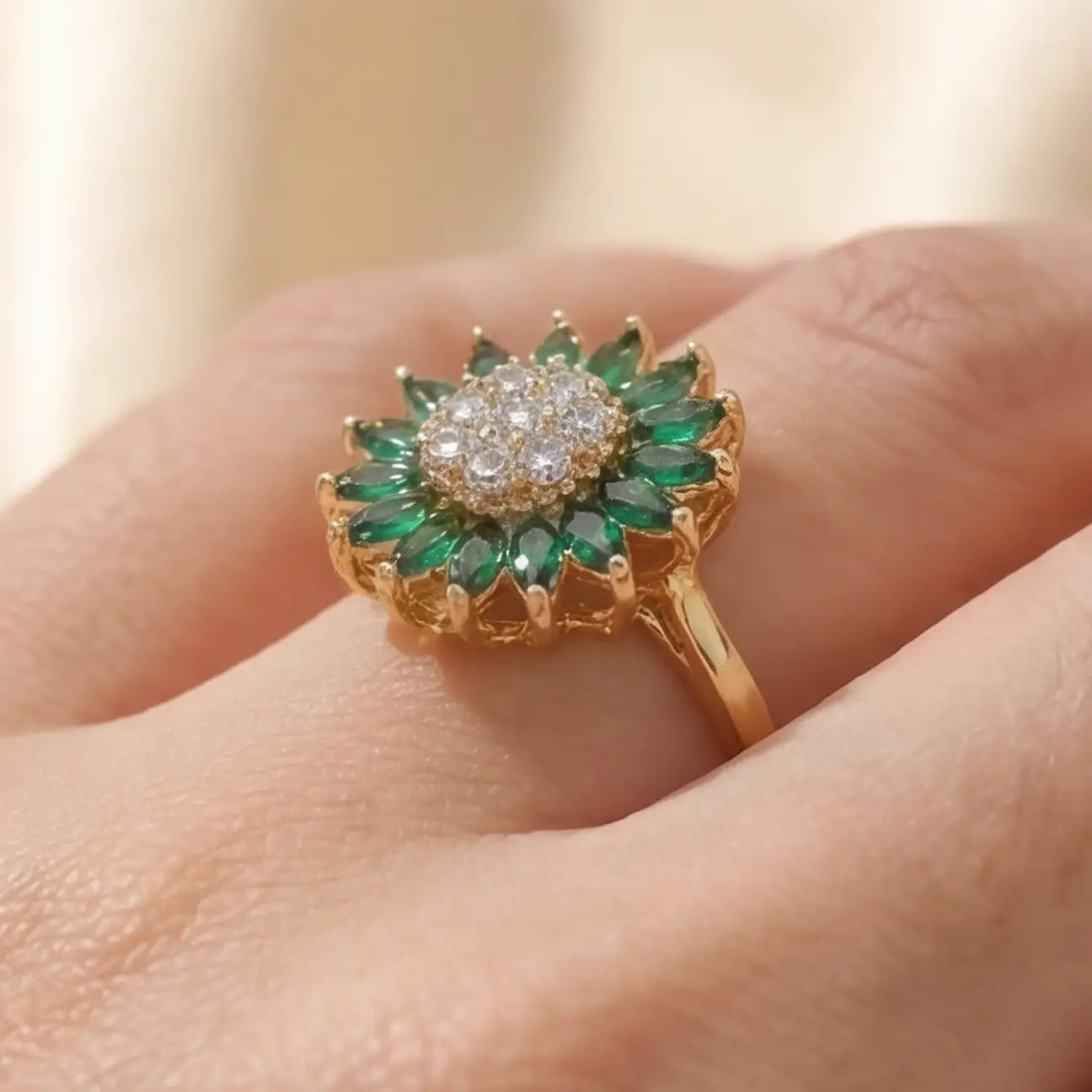 Gold sunflower calm ring with green marquise stones and crystal center worn on hand