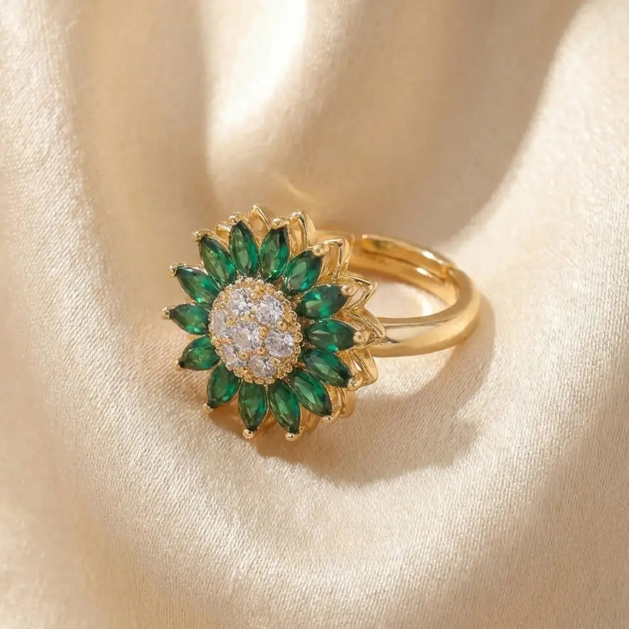 Gold sunflower calm ring with green marquise stones and crystal cluster center displayed on cream satin background