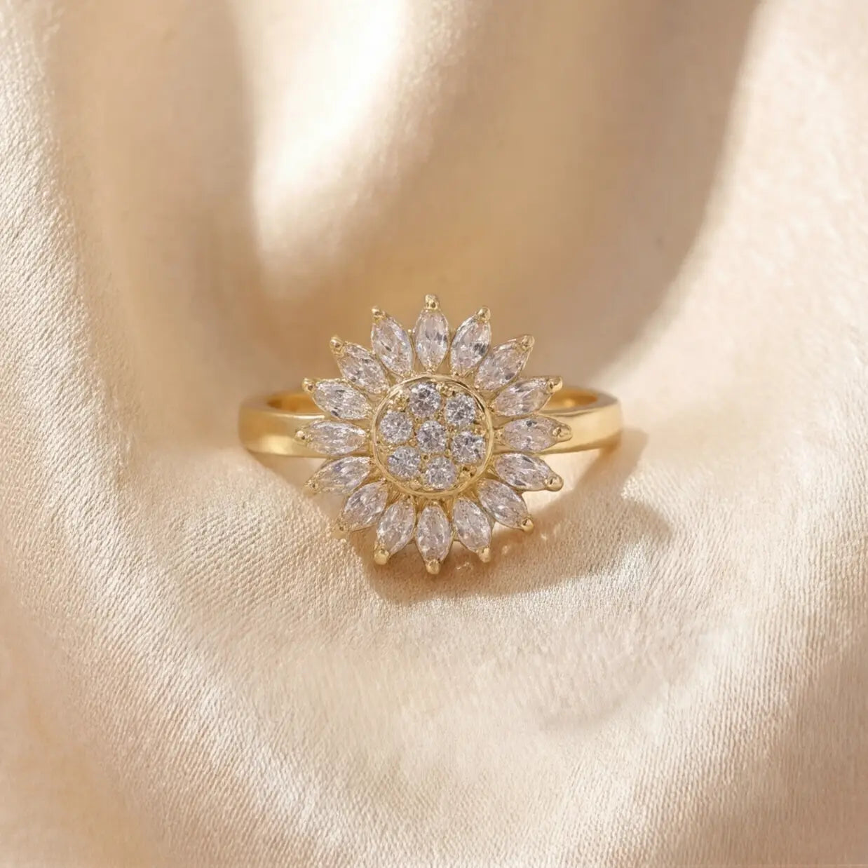 Gold sunflower calm ring with white marquise stones and pavé crystal center on cream satin background