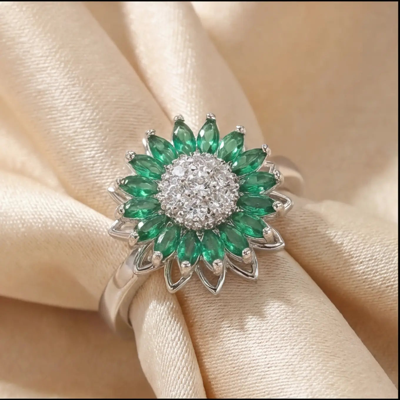 Silver sunflower calm ring with green marquise stones and crystal cluster center on cream satin background