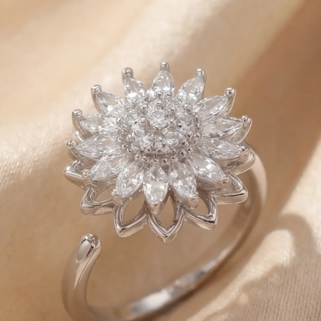 Silver sunflower calm ring with white marquise crystals and pavé center detail on cream satin background