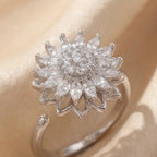 Silver sunflower calm ring with white marquise crystals and pavé center detail on cream satin background