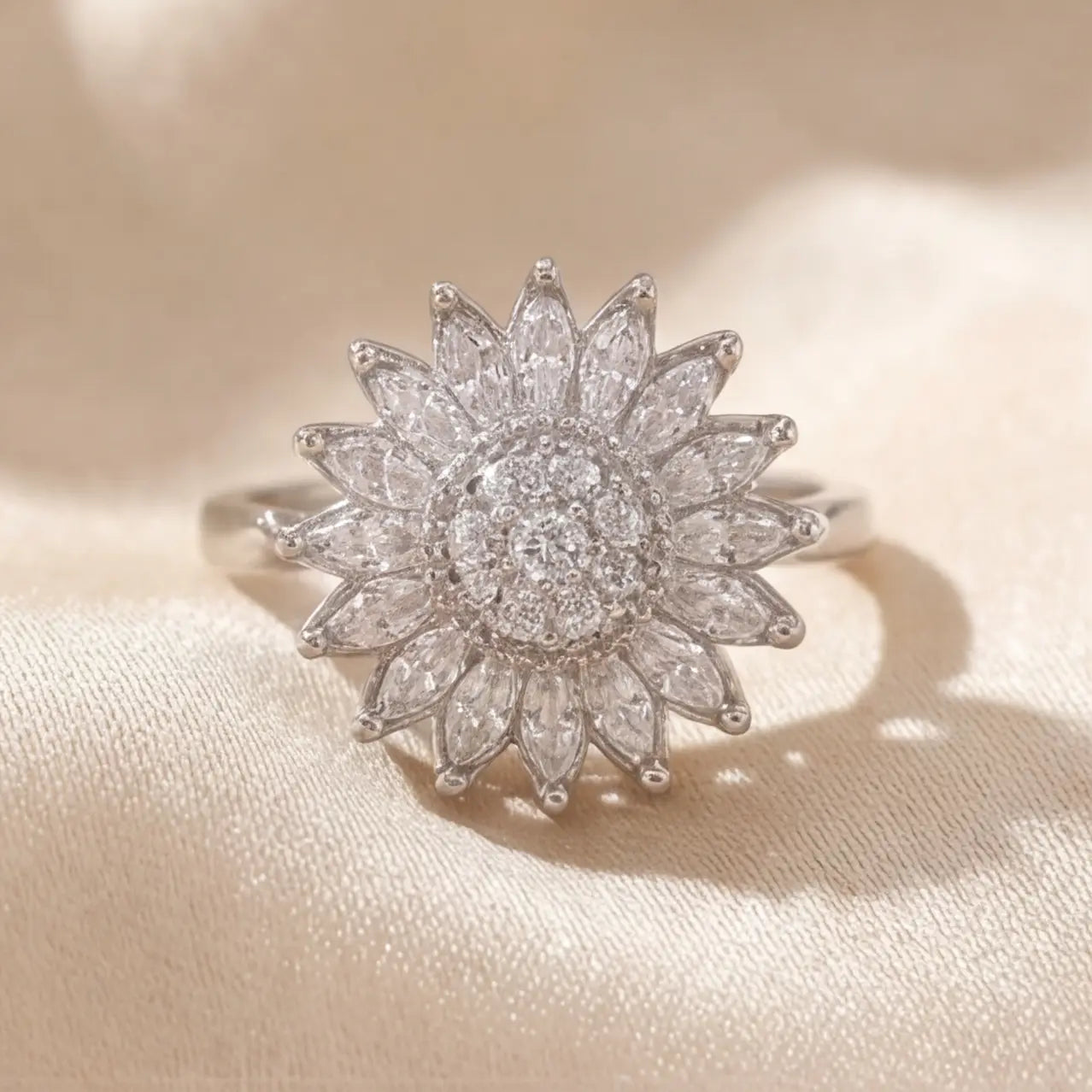 Silver sunflower calm ring with white marquise stones and crystal center displayed on cream satin background