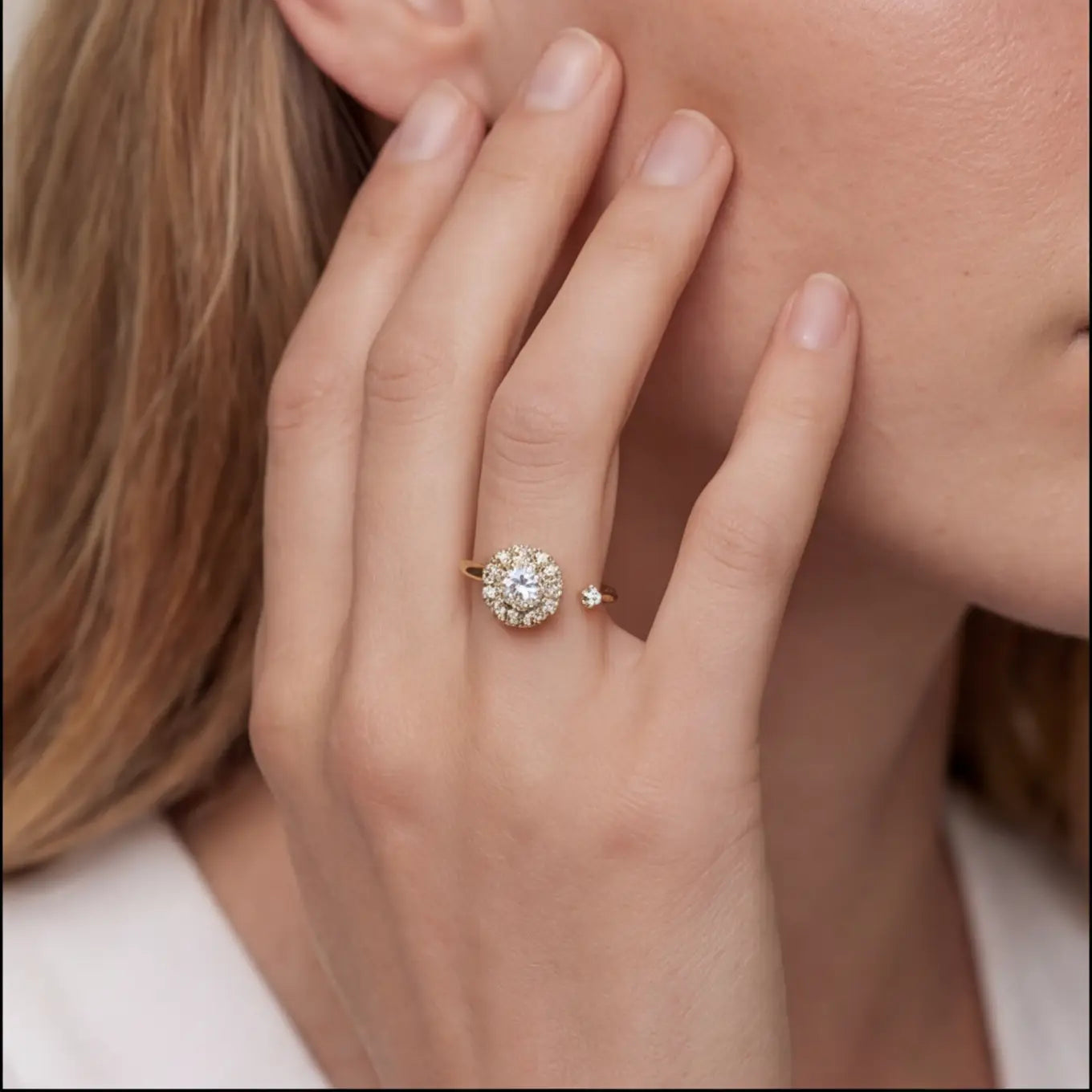 Gold flower cluster open calm ring with clear stones worn on hand near face