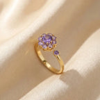 Gold flower cluster open calm ring with purple stones on silk background