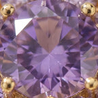 Macro close-up of purple center stone in gold flower cluster open calm ring