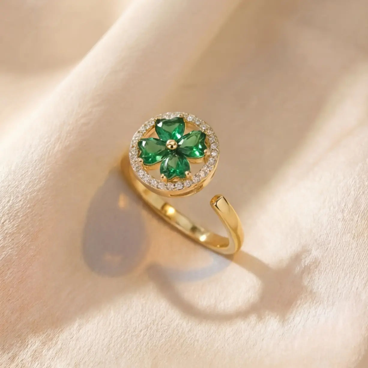 Angled view of Lunela Metà gold calm spinner ring with green clover stones and pavé halo