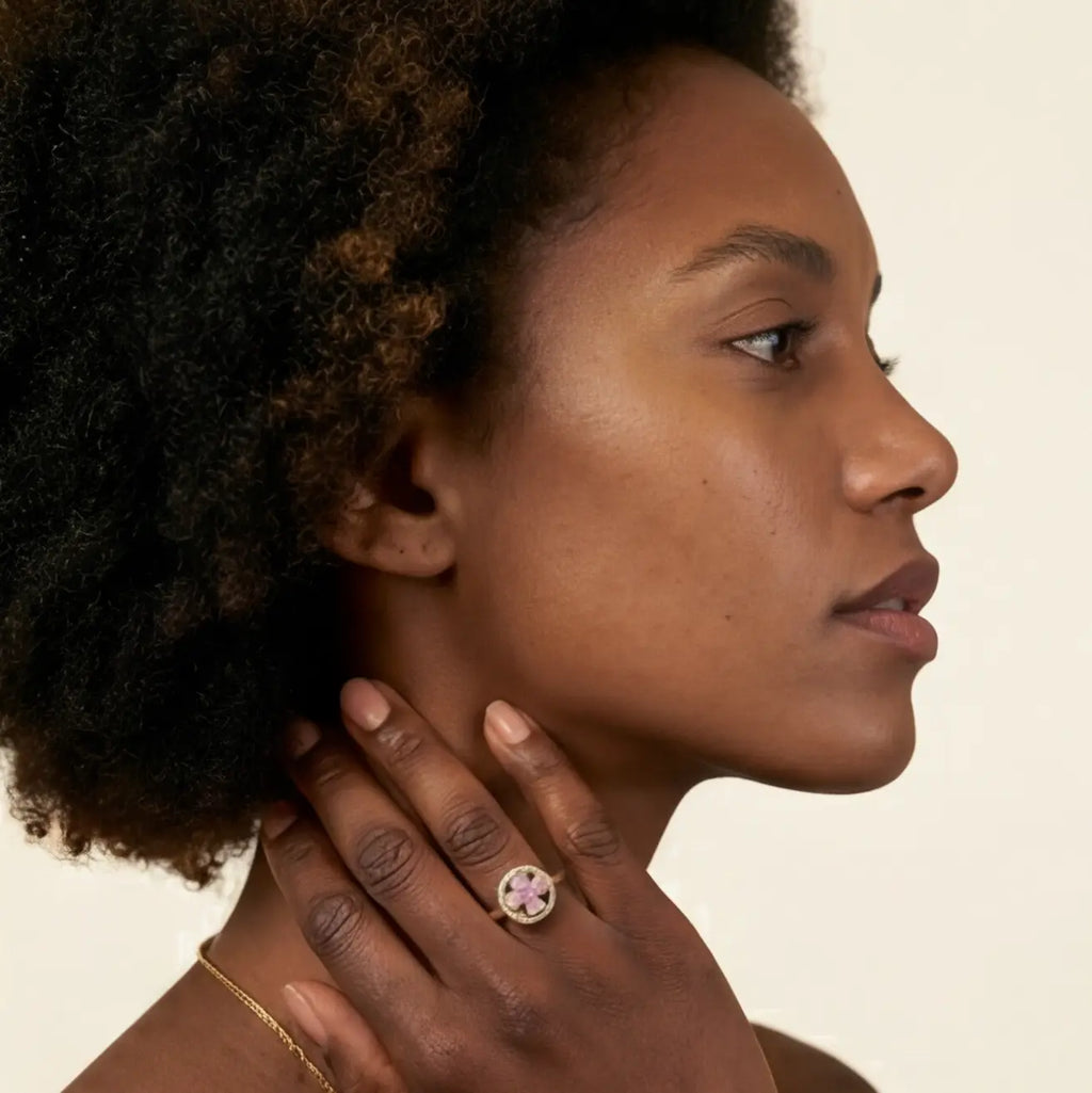 Side profile of model wearing Lunela Metà gold calm spinner ring with pink stone clover detail