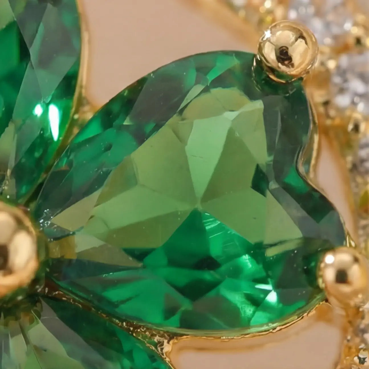 Macro close up of Lunela Metà green heart cut stone calm spinner ring with gold prong setting and pavé detail