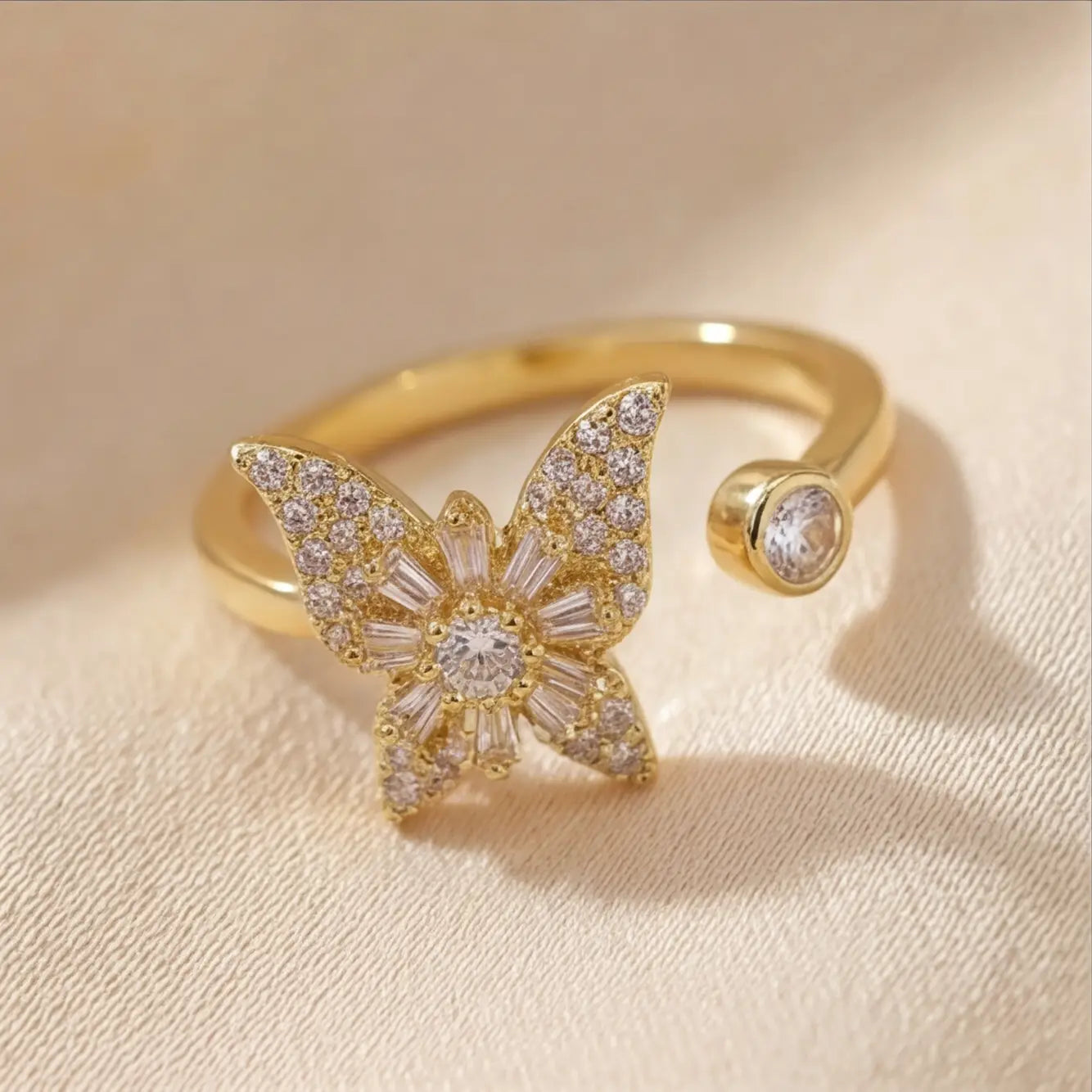 Raggio gold butterfly calm ring adjustable open band with pavé crystal stones on cream fabric background