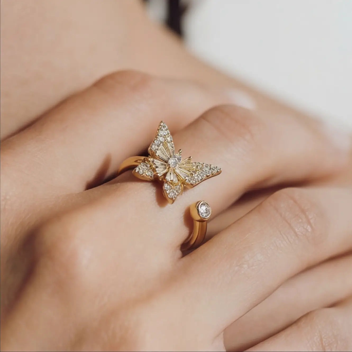 Raggio gold butterfly calm ring adjustable open band with crystal stones worn on hand close up