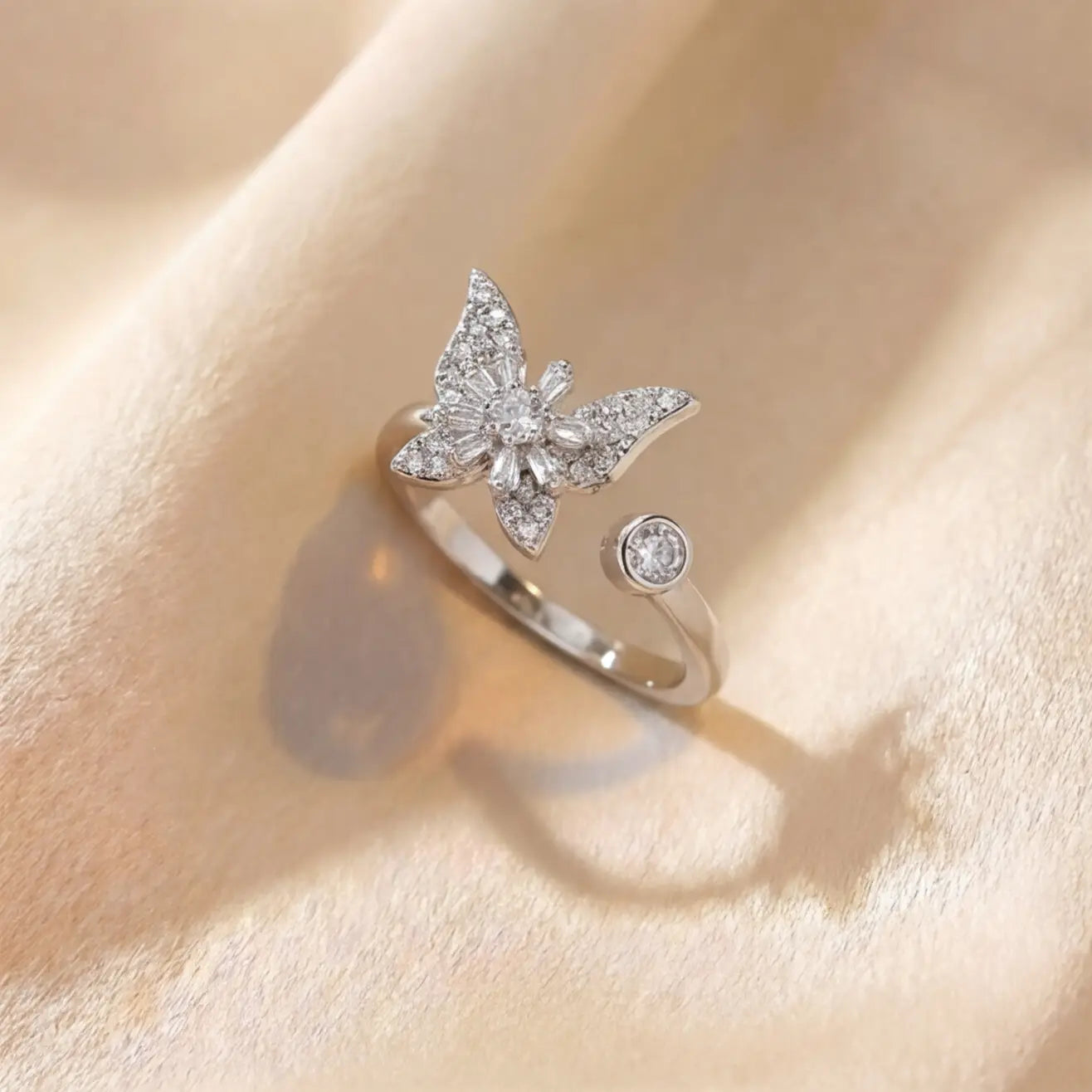 Raggio silver butterfly calm ring adjustable open band with pavé crystal stones on cream fabric background