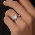 Silver Raggio sunburst calm ring with moonstone center worn on hand against dark background