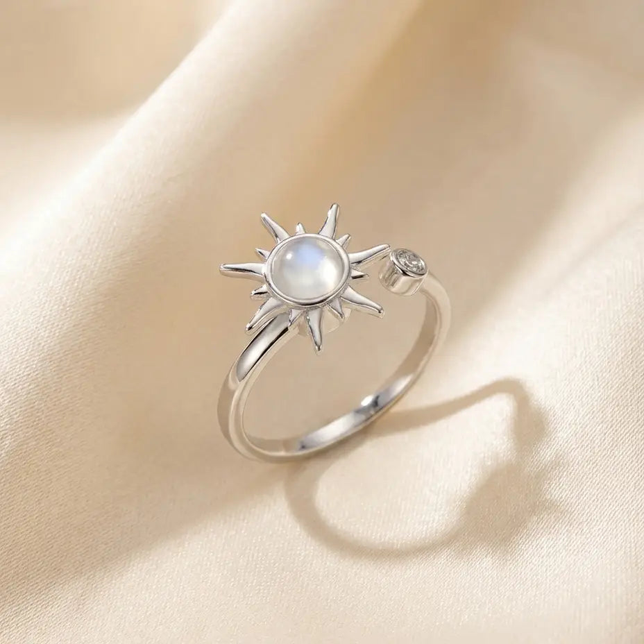 Silver Raggio sunburst calm ring with moonstone center on cream fabric background